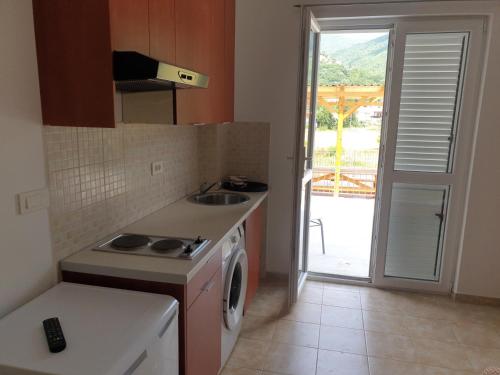 a kitchen with a stove and a washing machine at Apartmani Zlatko in Zelenika