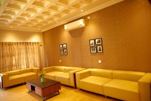 a living room with yellow couches and a table at Hotel King's Palace in Lubumbashi