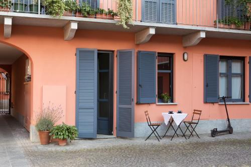 ein rosafarbenes Gebäude mit blauen Fensterläden und einem Tisch in der Unterkunft Casa da Gio', incantevole, nel cuore di Alba, con posto auto gratuito. in Alba