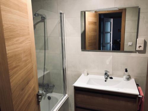 a bathroom with a sink and a shower with a mirror at Apartamento en Rianxo in Rianjo