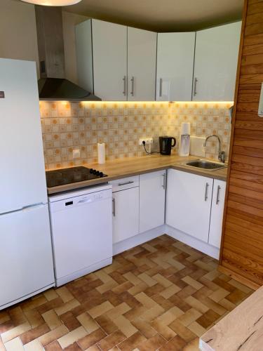 a kitchen with white cabinets and a wooden floor at maison blanche in Briançon