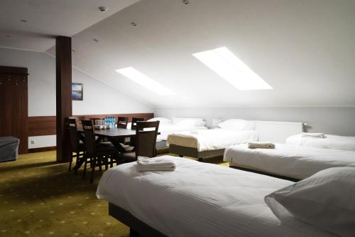 a hotel room with three beds and a table and chairs at Zajazd Kresowia in Sokółka