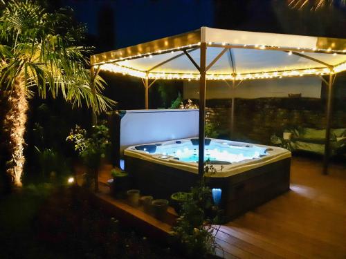 a jacuzzi tub in a backyard at night at Chambres d'Hotes Le 1900 in Val Couesnon