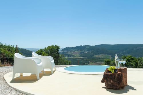 a patio with two white chairs and a pool at Bee Moinho in Sobral da Abelheira