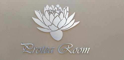 a sign of a white flower on a wall at Schnehage Self Catering in Bloemfontein