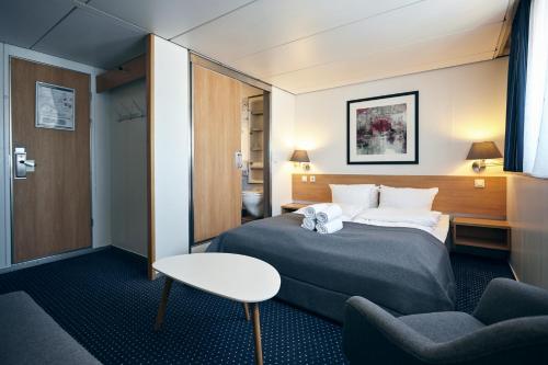 une chambre d'hôtel avec un lit, une table et des chaises dans l'établissement DFDS Ferry - Amsterdam to Newcastle, à IJmuiden