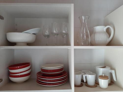 a white cabinet with plates and glasses and vases at Beautiful house and garden at Serra da Estrela, perfect for groups and families in Gouveia