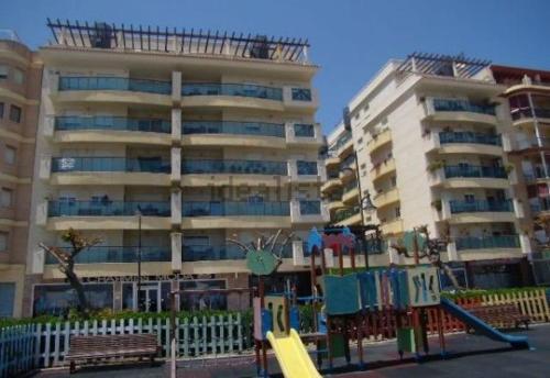 un parque infantil frente a un gran edificio de apartamentos en Avda España 200, en Estepona