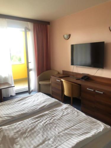 a hotel room with a bed and a desk with a flat screen tv at Apartmány wellness Frymburk in Frymburk