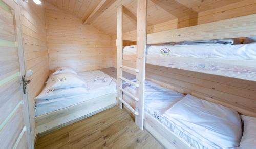 kilka łóżek piętrowych w drewnianym pokoju w obiekcie Rajskie Siedlisko w mieście Smyków