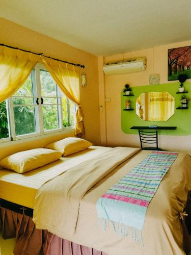 a bedroom with a large bed and a window at ภูร์ชรินท์ รีสอร์ท in Ban Than Phra