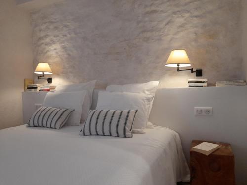 a bedroom with a white bed with two pillows and two lamps at Les Guillaume Rey in Oppède