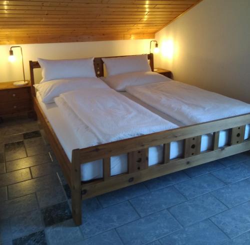 Cama grande de madera en habitación con 2 luces en Ferienwohnungen Haubner, en Litschau
