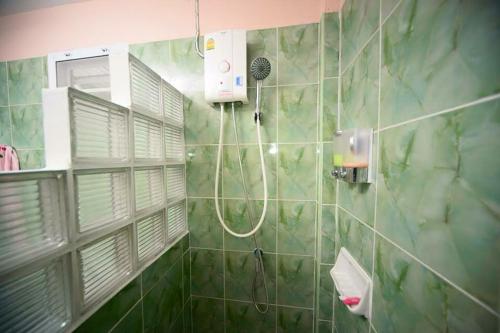 a green tiled bathroom with a shower and a window at ภูร์ชรินท์ รีสอร์ท in Ban Than Phra