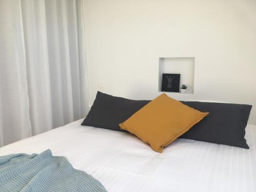 Una cama con almohadas negras y amarillas. en Huis van Silvie, en Koolskamp