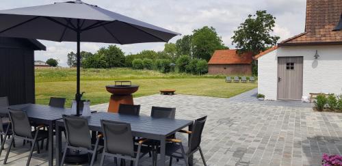 a black table and chairs with an umbrella on a patio at Huis van Silvie in Koolskamp