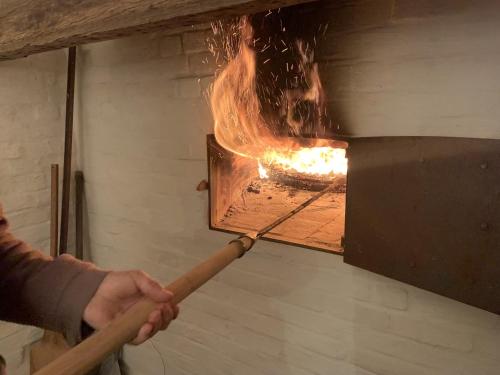 a person holding a stick in a fire oven at Huis van Silvie in Koolskamp