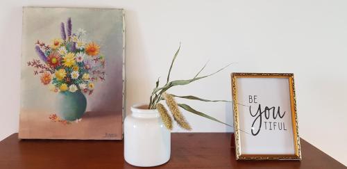 a table with a vase of flowers and a picture at Huis van Silvie in Koolskamp