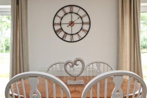 a dining room with a clock on the wall at Otters Holt in Saint Merryn