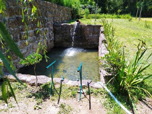 a small pond in a stone wall with a waterfall at Casas Vale Martinho in Santa Comba Dão