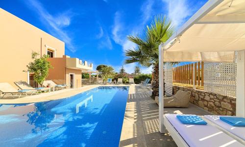 uma piscina ao lado de uma casa com uma palmeira em Island Villa Heated Pool em Georgioupolis