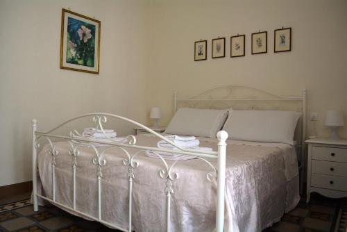 sypialnia z białym łóżkiem, komodą i obrazami w obiekcie Casa Il Campanile w mieście Ostuni