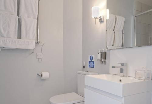 a white bathroom with a sink and a toilet at Saddlers B&B in Funtington