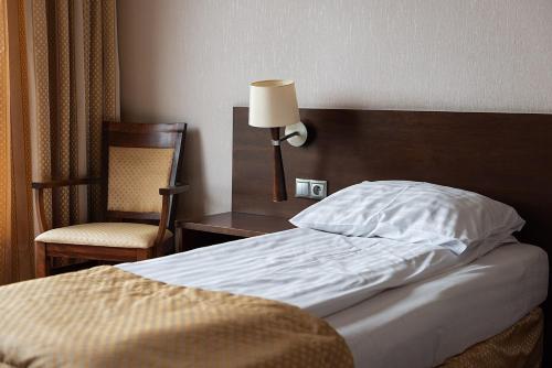a bedroom with a bed and a chair and a lamp at Hotel Police in Police Mostowe