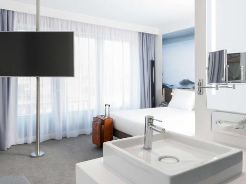 a hotel room with a sink and a bed at Novotel Charleroi Centre in Charleroi