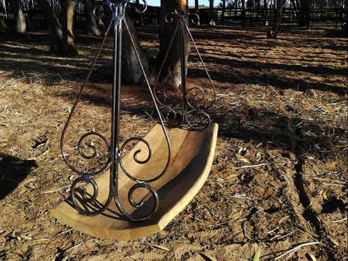 a metal object sitting on the ground next to a tree at Oorgenoeg in Langebaan in Langebaan
