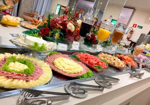 a buffet with many different types of food on a counter at Hotel Golden Park Uberaba in Uberaba
