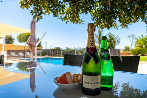 two bottles of champagne and a bowl of fruit on a table at Beach Villa - oceanfront villa Martinhal in Sagres