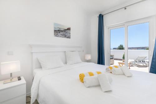 a white bedroom with a large bed and a window at Beach Villa - oceanfront villa Martinhal in Sagres