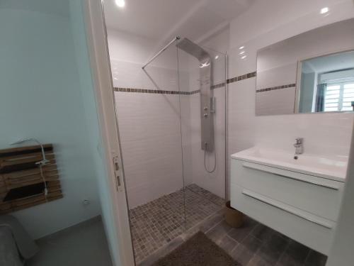 ein weißes Bad mit einer Dusche und einem Waschbecken in der Unterkunft Alizeva in Le Diamant