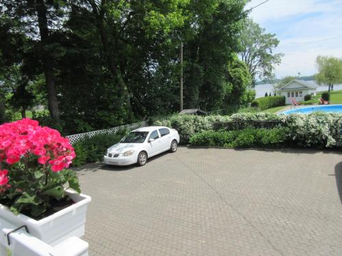a white car parked in a parking lot with flowers at Gîte Saint-Laurent in Trois-Rivières
