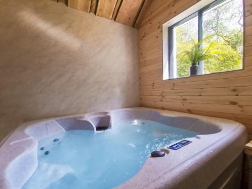 a jacuzzi tub in a room with a window at Woodlands Family Retreat Windermere with Hot Tub and Sauna in Windermere