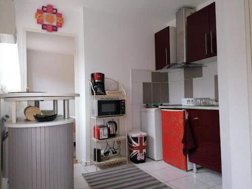 La cuisine est équipée d'un réfrigérateur rouge et d'un four micro-ondes. dans l'établissement Charmante Maisonnette indépendante avec parking 5 mn Rouen, à Franqueville-Saint-Pierre