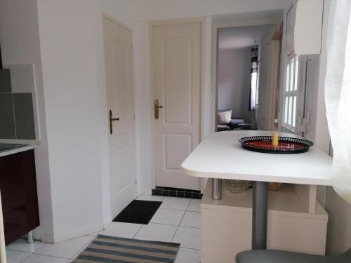 une petite cuisine avec un comptoir blanc et un évier dans l'établissement Charmante Maisonnette indépendante avec parking 5 mn Rouen, à Franqueville-Saint-Pierre