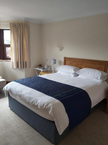 a bedroom with a large bed with blue and white sheets at Byerley House in Newmarket