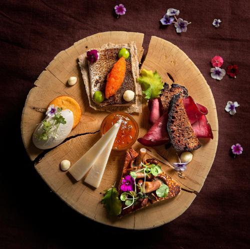 a wooden plate with different types of food on it at Lapland Hotels Saaga in Ylläsjärvi