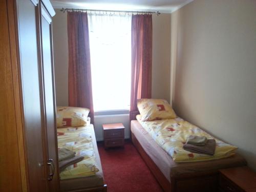 Habitación pequeña con 2 camas y ventana en Hotelik Parkowy, en Legnica