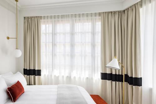a bedroom with a bed and a large window at Kimpton - St Honoré Paris by IHG in Paris