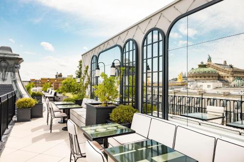a balcony with tables and chairs and a view of the city at Kimpton - St Honoré Paris by IHG in Paris