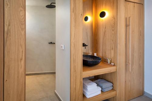 a bathroom with a sink in a wooden wall at Callia Retreat Suites - Adults Only in Fira