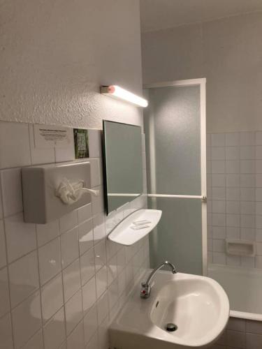 une salle de bain avec un lavabo et un miroir dans l'établissement Logis Hotel Restaurant des Voyageurs, au Malzieu-Ville