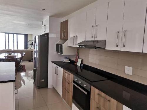 a kitchen with white cabinets and a black refrigerator at Apartment 13 Santana Pebbles, 164 South Beach Road, La Mercy in La Mercy
