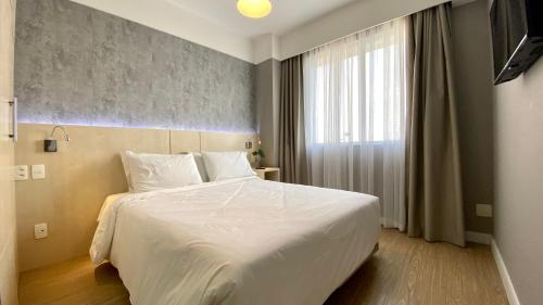 a bedroom with a large white bed and a window at STD - Anora Spaces - Stadium Alphaville in Barueri