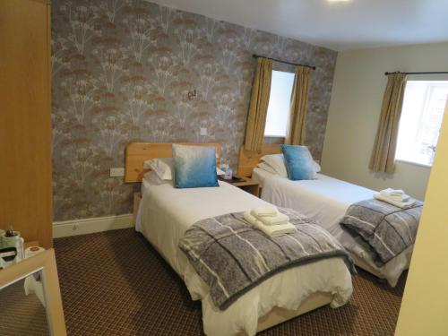 a hotel room with two beds with blue pillows at The Roebuck Inn in Chapel en le Frith