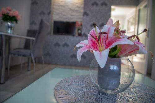 a vase with pink flowers sitting on a table at DIS apartman 1 in Kruševac