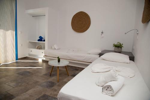 two beds in a white room with a table at Artemis in Makry Gialos